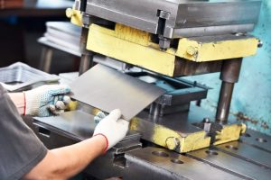 worker at manufacture workshop operating metal press machine